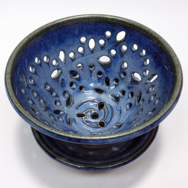 An overhead view of a blue ceramic bowl with decorative cutouts by Phyllis Seidner.
